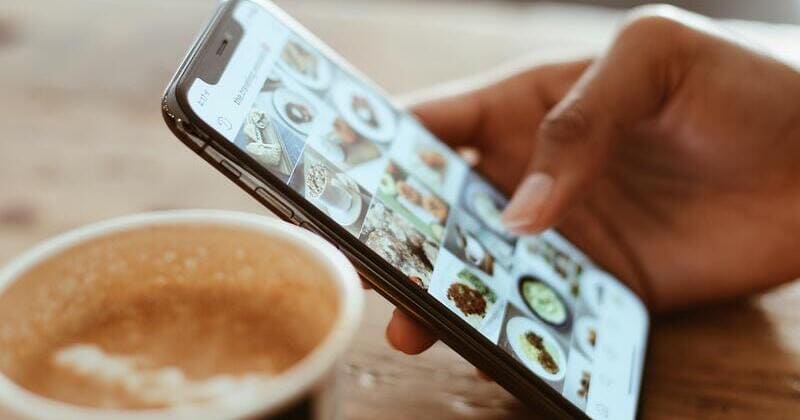 móvil con aplicación social de imágenes con un café de fondo